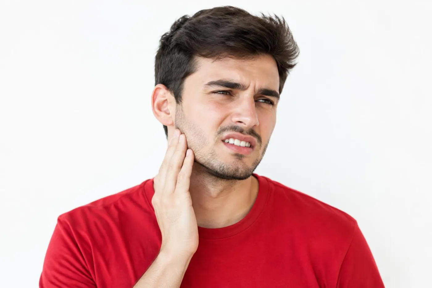 Young man touching his jaw with signs his wisdom teeth are coming in